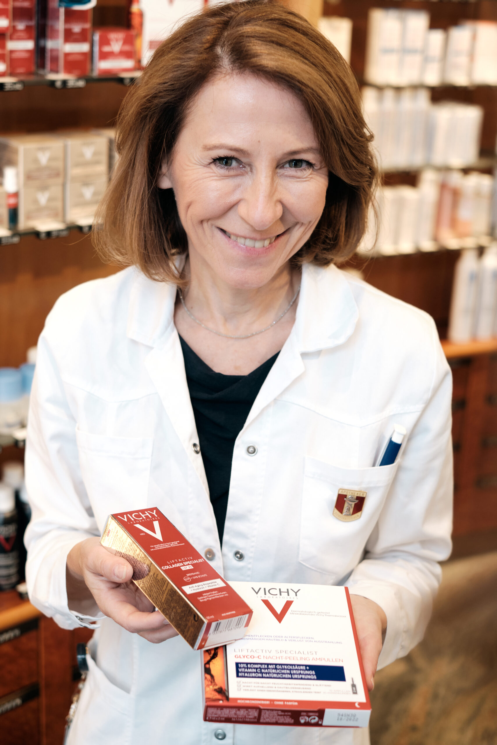 team-sante-schwenk-by-wolfgang-lehner_XH16303 Pharmazeutin zeigt Kosmetikprodukte her.